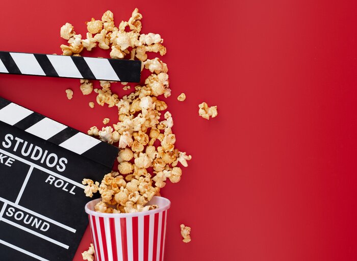 Bild Clapper board with popcorn against red background,Cinema minimal concept,top,view