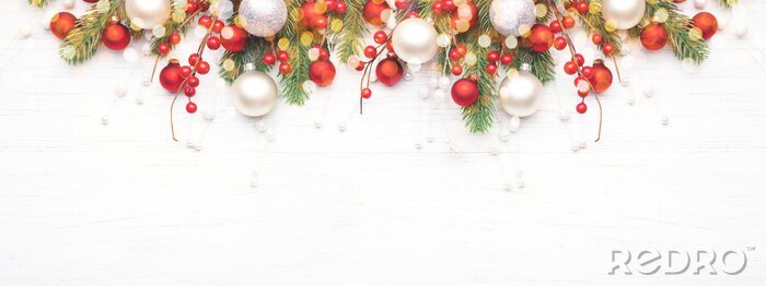 Bild Classic Christmas composition with fir branches and white and red baubles on white wooden background. Noel banner for website.
