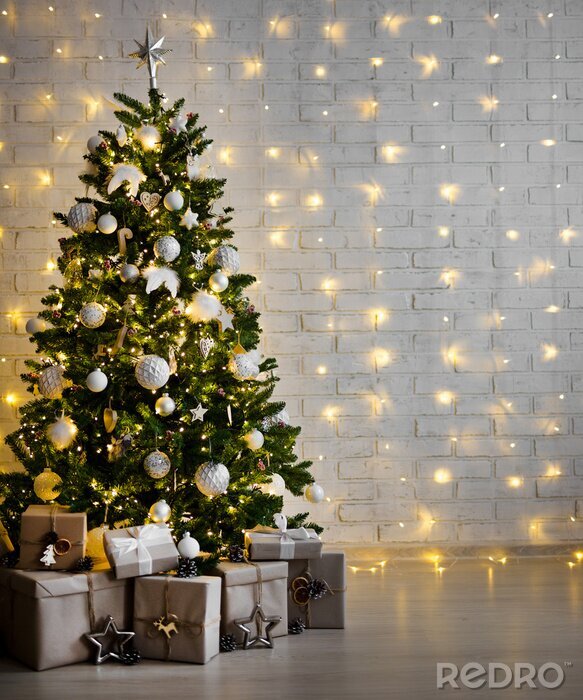 Bild decorated christmas tree with white balls, garlands and gift boxes over white brick wall