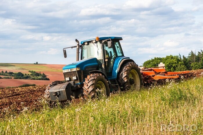 Bild Ein blauer Traktor arbeitet an einem klaren Tag auf einem Feld.