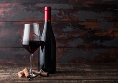 Glas Wein und Flasche vor dem Hintergrund des Holzes