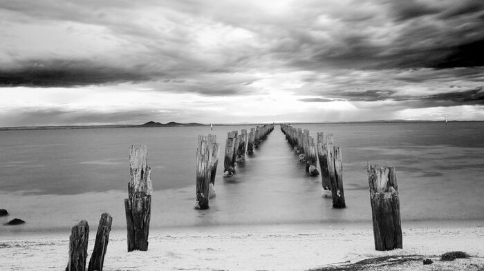Bild Glattes Meer mit Holzpfahlen