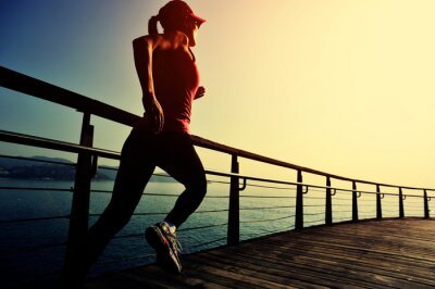 Bild junge Fitnessfrau, die auf Sonnenaufgang-Strandpromenade läuft
