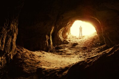 Mensch am Eingang der beleuchteten Höhle
