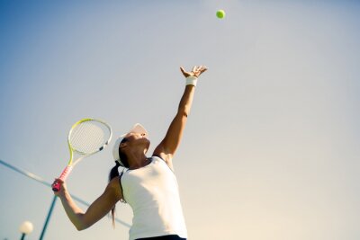Bild Servierende Tennisspielerin auf Himmelhintergrund