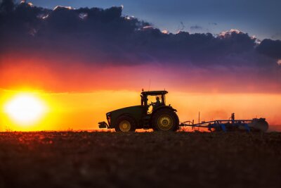 Traktor arbeitet bei Sonnenuntergang