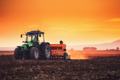 Traktor bei Sonnenuntergang auf dem Feld