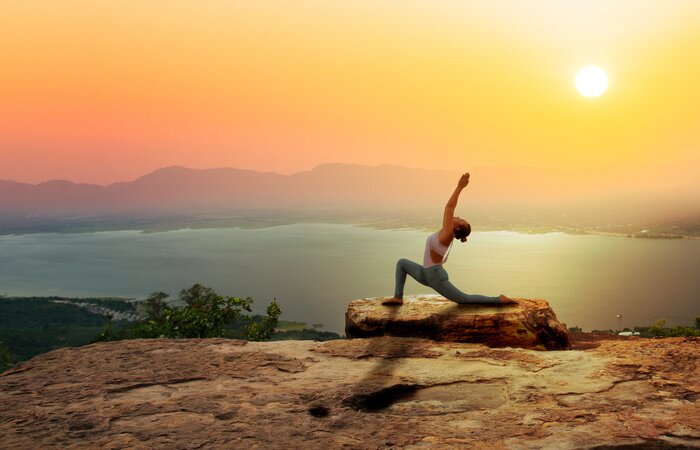 Bild Yoga bei Sonnenaufgang mit einer Berglandschaft im Hintergrund