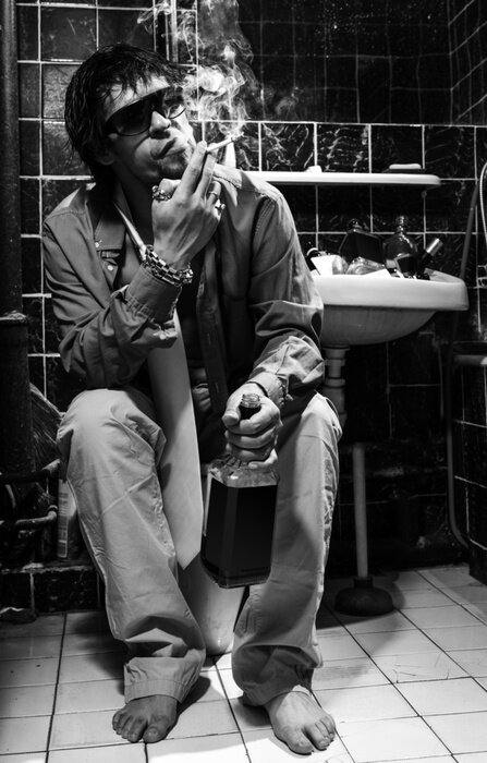 Fototapete Betrunkener Mann sitzt in einer Toilette mit einer Flasche Alkohol