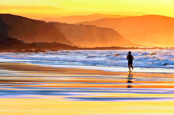 Fototapete Ein Läufer am Strand bei Sonnenuntergang