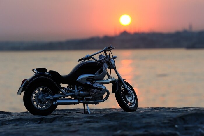 Fototapete Ein Motorrad am Meer bei Sonnenuntergang