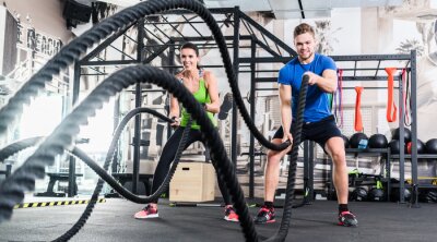 Fototapete Eine Frau und ein Mann trainieren im Fitnessstudio mit einem Seil