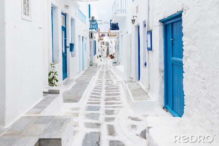 Fototapete Eine weiße griechische Straße mit blauen Türen und Fensterläden