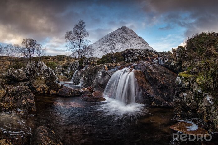 Fototapete Erstaunliche Naturlandschaft von Schottland.  Ein Wasserfall mit schneebedecktem Berg im Hintergrund.  Schottland ist einfach so schön.