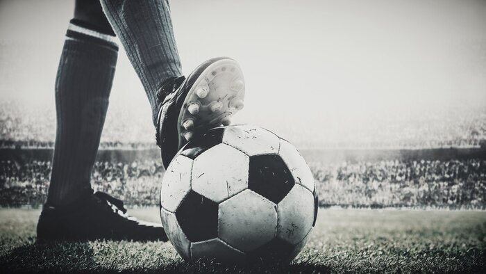 Fototapete Feet of soccer player tread on soccer ball for kick-off in the stadium black and white