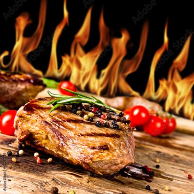Fototapete Gegrillte Rindersteaks mit Flammen im Hintergrund