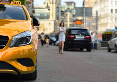 Gelbes Taxi und Frau im Hintergrund