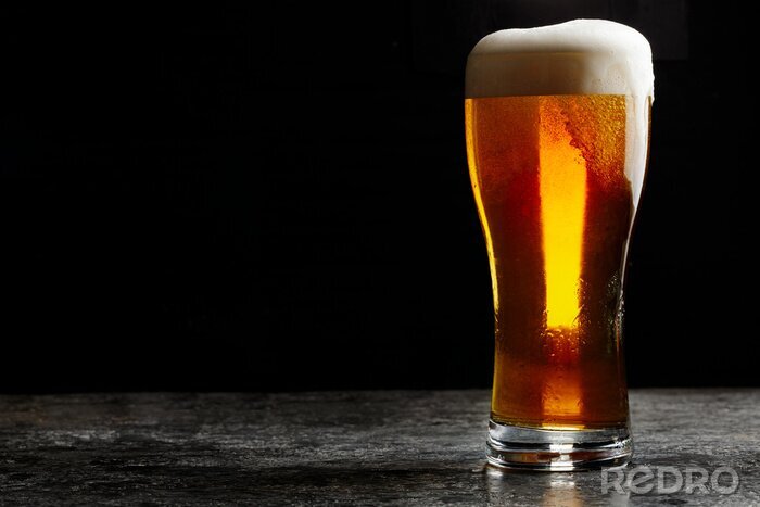 Fototapete Glas mit Bier auf dunklem Hintergrund
