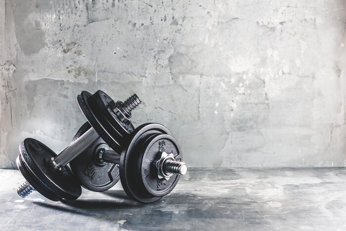 Fototapete Hanteln und Gewichte vor einem Betongegenstand