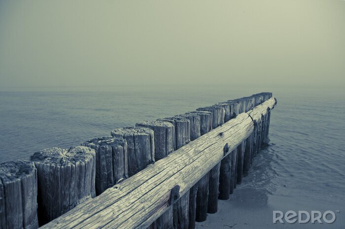 Fototapete Hölzerner Wellenbrecher am Meer