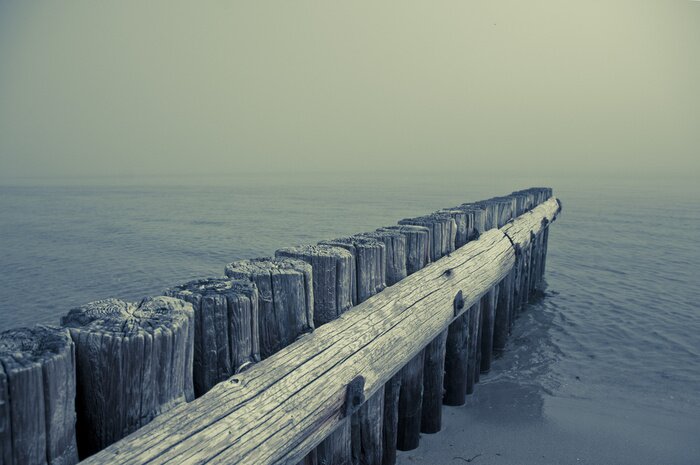 Fototapete Hölzerner Wellenbrecher am Meer