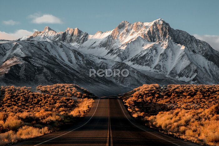 Fototapete Landschaft mit einer Straße vor dem Hintergrund schneebedeckter Berggipfel