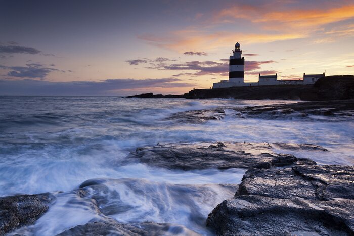 Fototapete Leuchtturm am felsigen Strand
