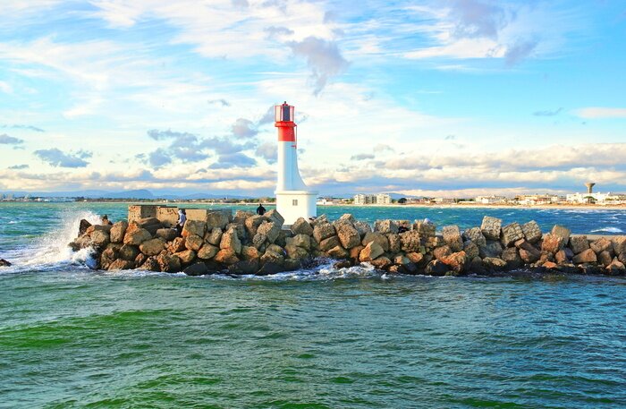 Fototapete Leuchtturm auf steinigem Wellenbrecher