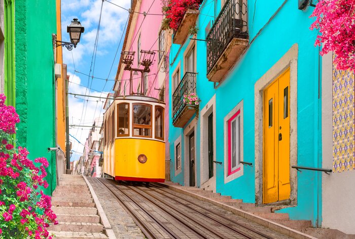 Fototapete Lisbon, Portugal - Yellow tram on a street with colorful houses and flowers on the balconies - Bica Elevator going down the hill of Chiado.