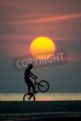Fototapete Mann mit einem Fahrrad bei Sonnenuntergang