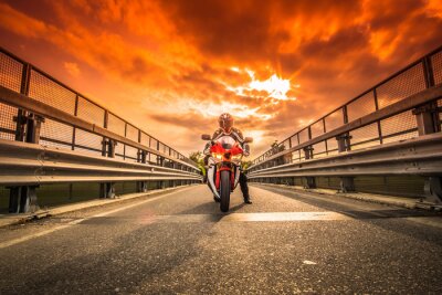 Fototapete Moto da strada pronta alla partenza sotto un cielo rosso al tramonto