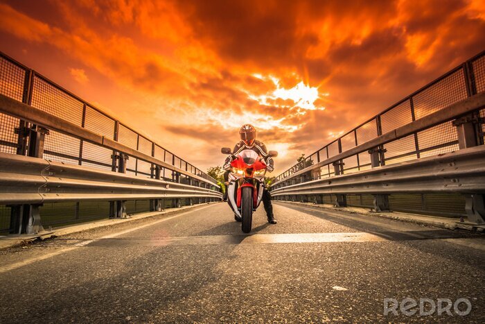 Fototapete Moto da strada pronta alla partenza sotto un cielo rosso al tramonto
