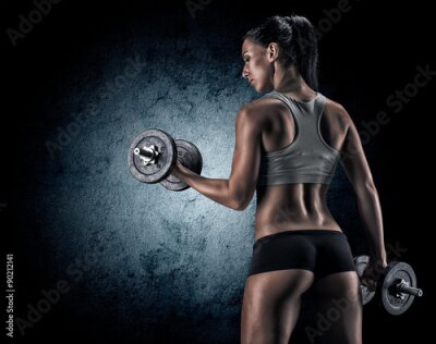 Fototapete Muscular woman in studio on dark background