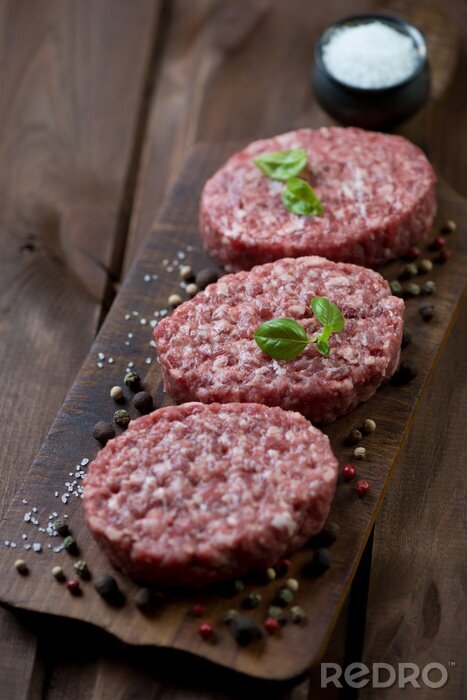 Fototapete Raw beef cutlets with various spices, rustic wooden background
