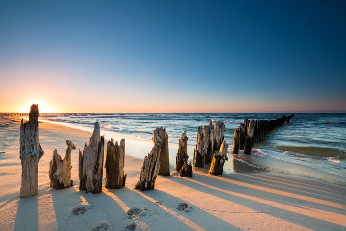 Fototapete Sonnenuntergang am Ostseestrand und altes hölzernes Wellenbrecher