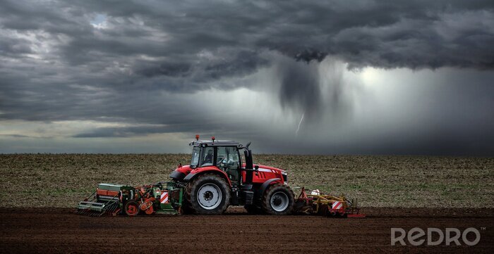 Fototapete Traktor auf dem Feld während des Sturms
