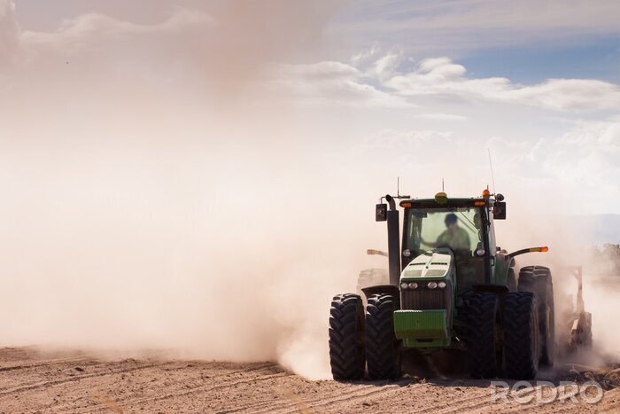 Fototapete Traktor auf einem Feld voller Staub