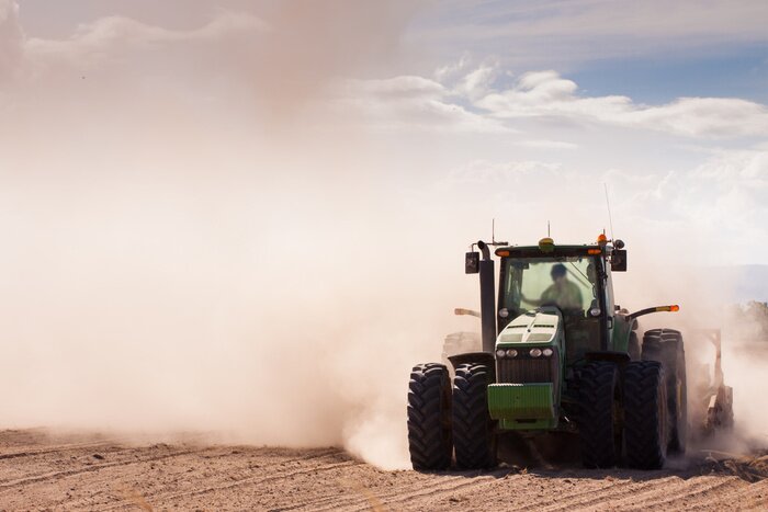 Fototapete Traktor auf einem Feld voller Staub