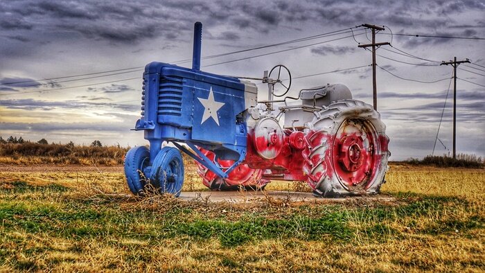 Fototapete Traktor in Texas-Farbe auf einem Feld