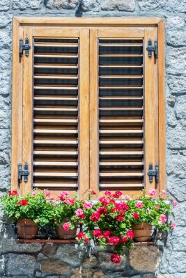 Fototapete Typical window of a  stone house with wooden shutters closed and