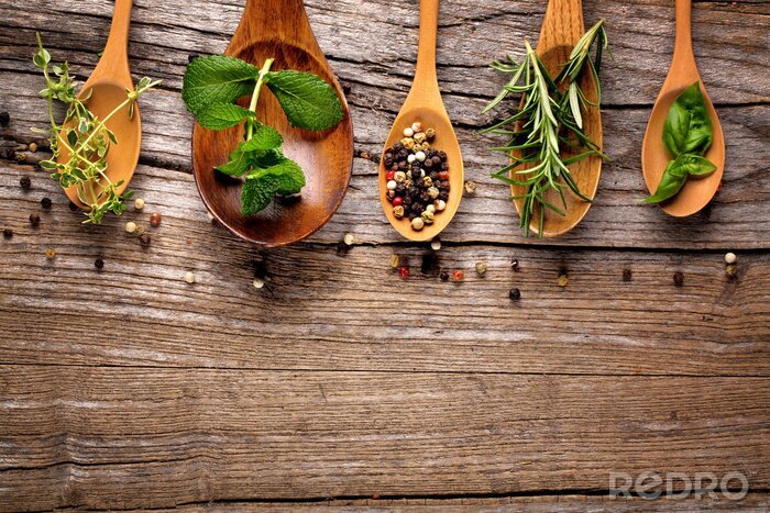 Fototapete Verschiedene Gewürze und Kräuter auf Holzlöffeln angerichtet