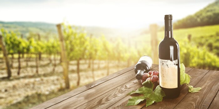 Fototapete Wein auf dem Tisch vor dem Hintergrund des Weinberges