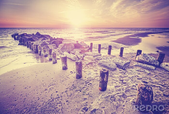 Fototapete Wellenbrecher aus Holz und Steinen am Strand