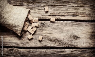 Poster Auf Holzbrettern verstreute Rohrzuckerwürfel.