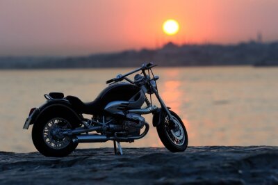 Poster Ein Motorrad am Meer bei Sonnenuntergang