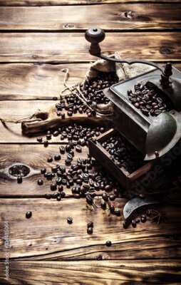 Poster Eine klassische Handmühle, umgeben von verstreuten Kaffeebohnen.