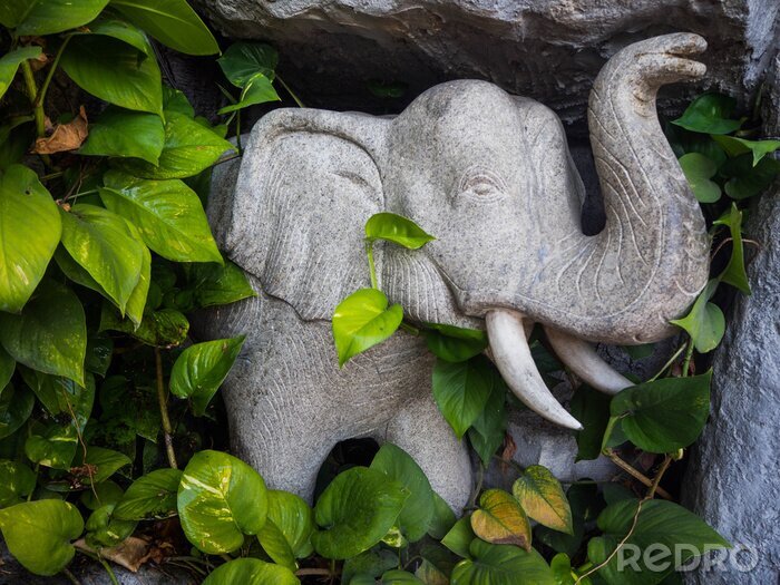 Poster Elefant aus Stein inmitten der Blätter