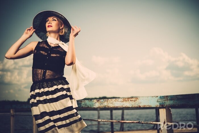 Poster Frau mit Hut auf einer Seebrücke