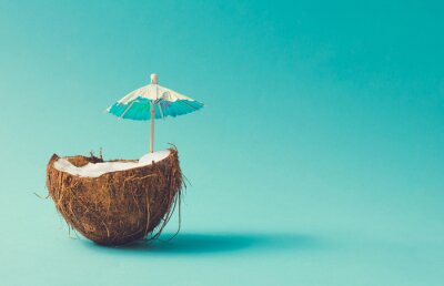 Poster Getränk mit einem Regenschirm in einer halben Kokosnuss