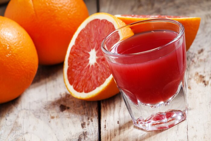 Poster Glas Saft vor dem Hintergrund von roten Orangen